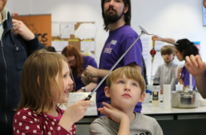 Kids using a magnet to hold up a metal spoon